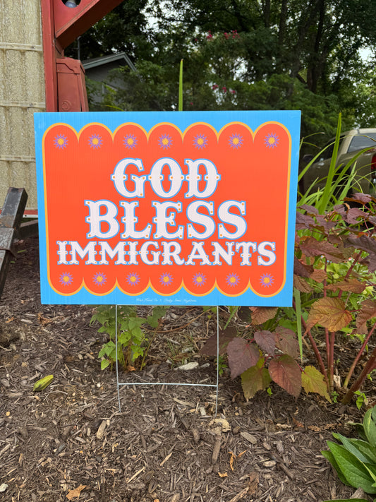Outdoor sign with 'God Bless Immigrants' text on a garden background
